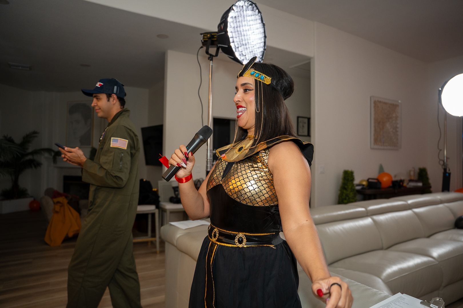 A guest in a black-and-gold Egyptian-inspired costume speaking into a red microphone