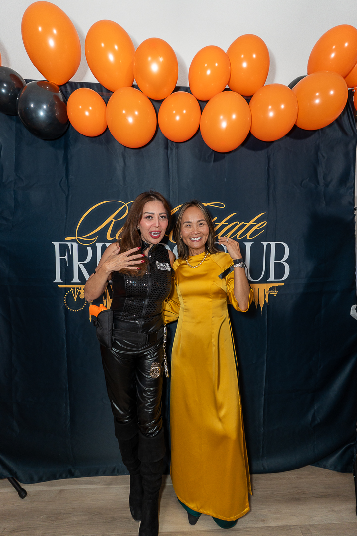 Two friends in black and yellow outfits posing at the REFC backdrop