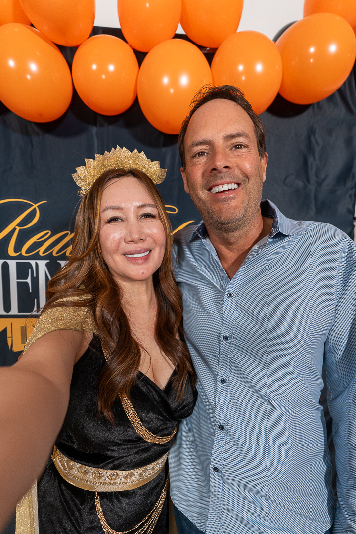 Two smiling friends taking a selfie beneath the orange and black REFC balloons