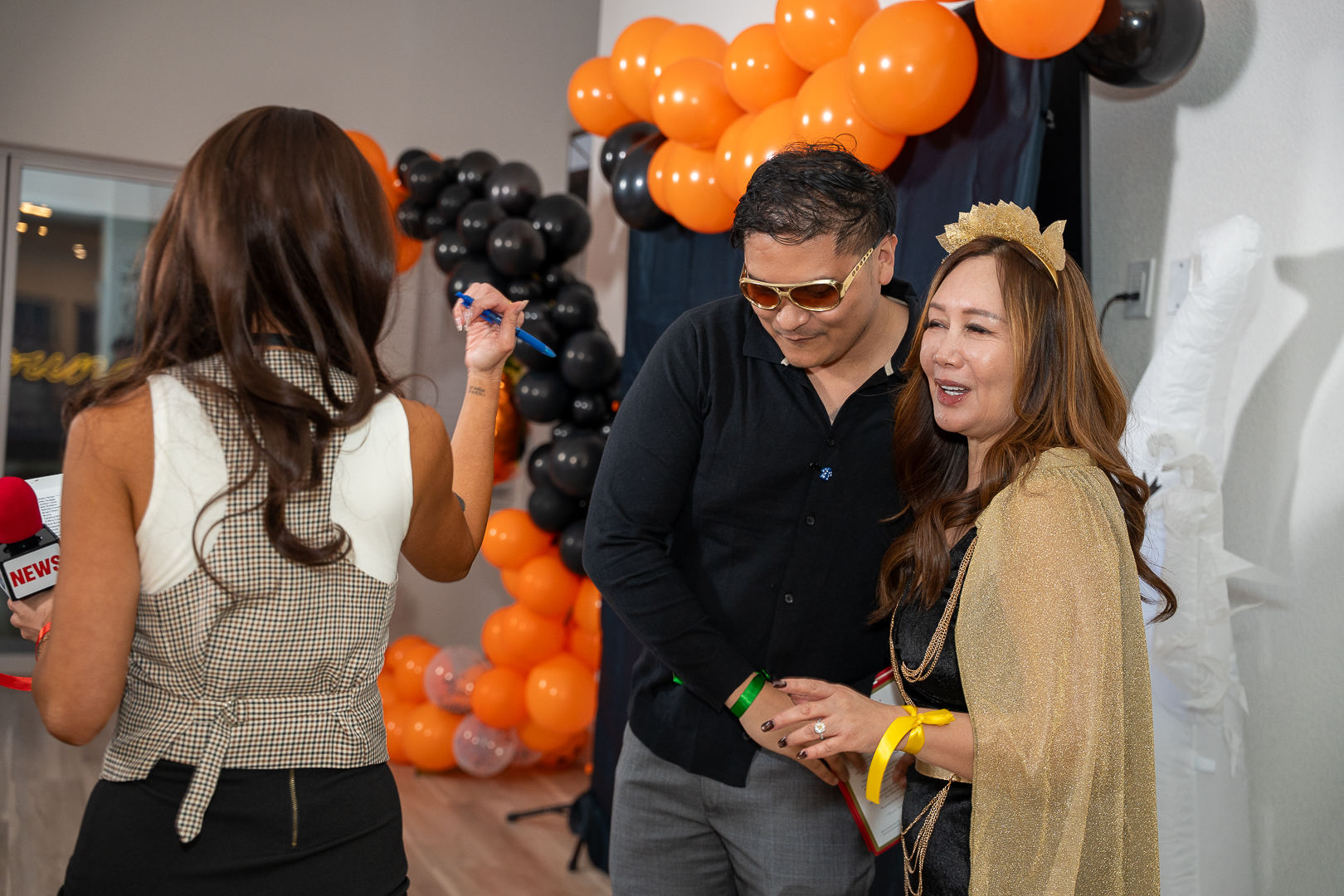 Friends chatting beside the orange and black balloon arch