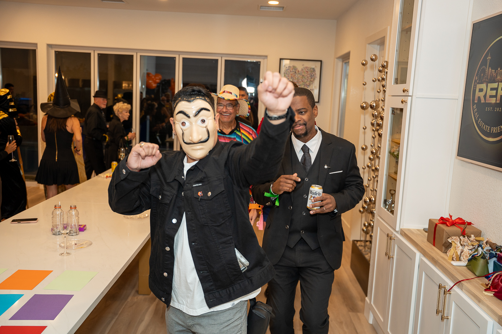 A masked guest raising a drink with friends during REFC's anniversary celebration