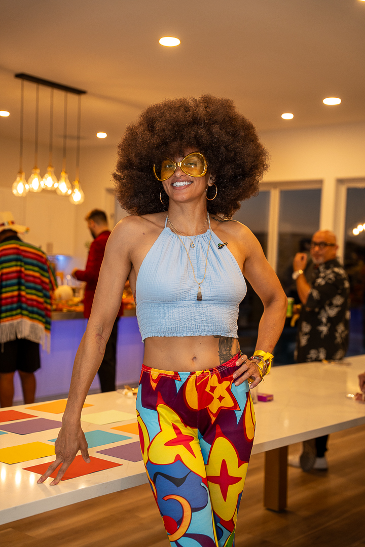 A smiling guest in a disco-inspired costume with colorful trousers