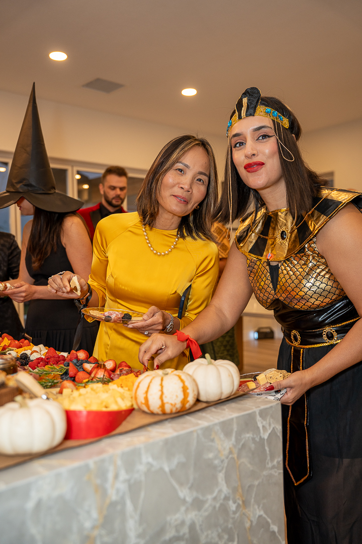 Friends in yellow and Egyptian-inspired outfits posing beside the Halloween buffet
