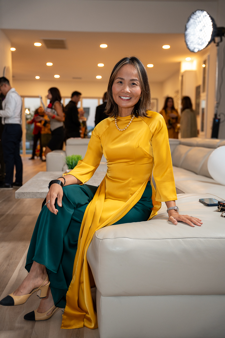 A guest in a yellow áo dài and green trousers posing on the sofa