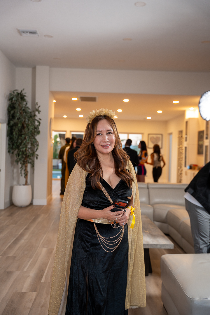 A guest in a black-and-gold gown posing beside the sofa at the mixer