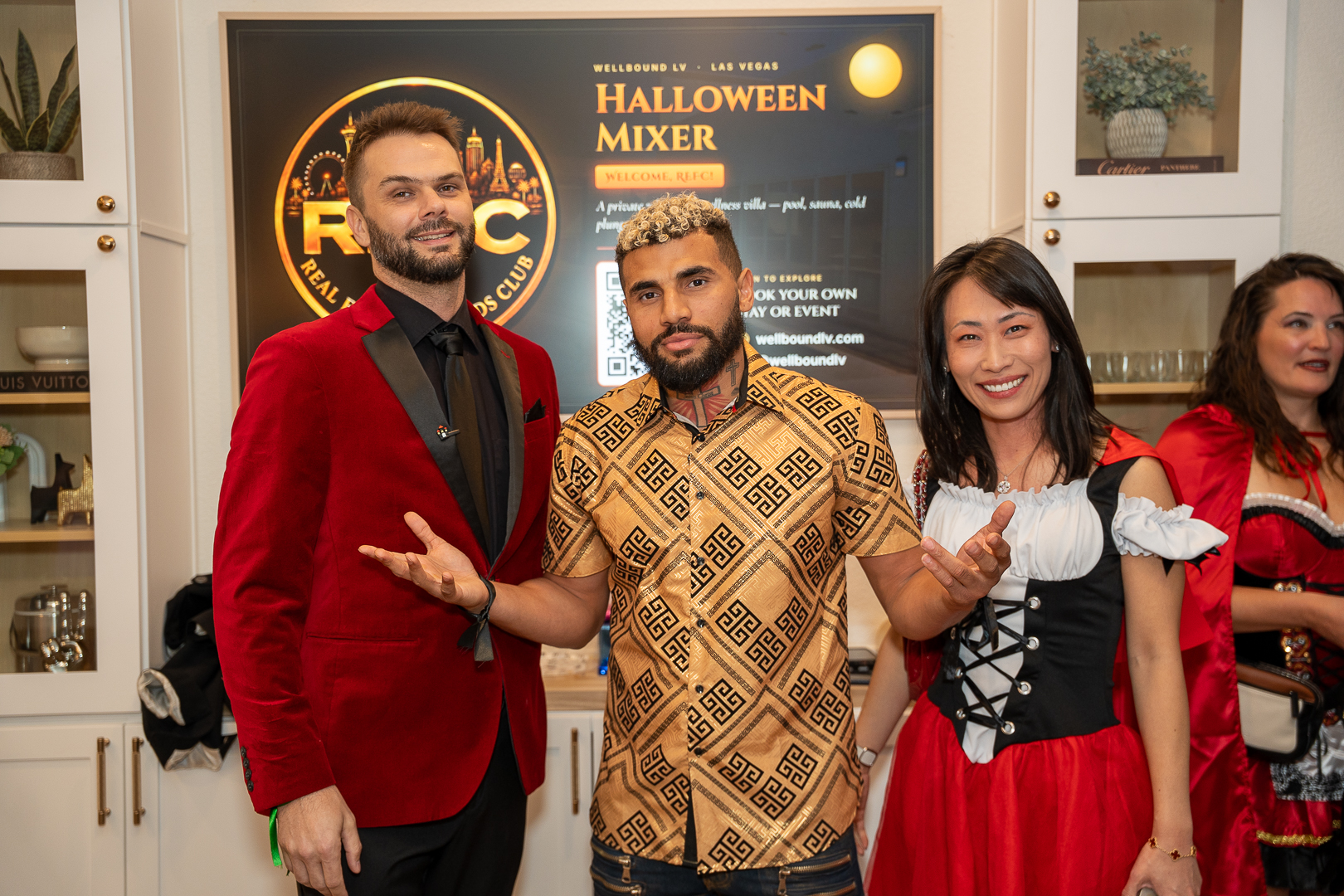 Friends posing beside the REFC Halloween Mixer anniversary sign