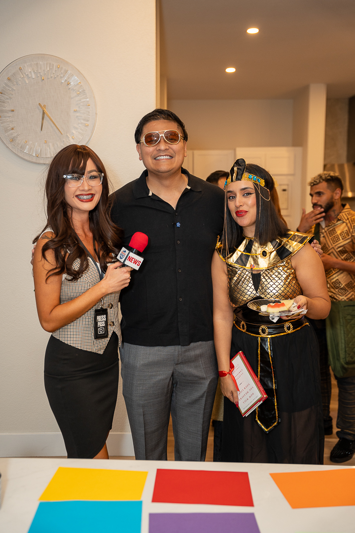 Three guests posing beside the kitchen island with a red microphone