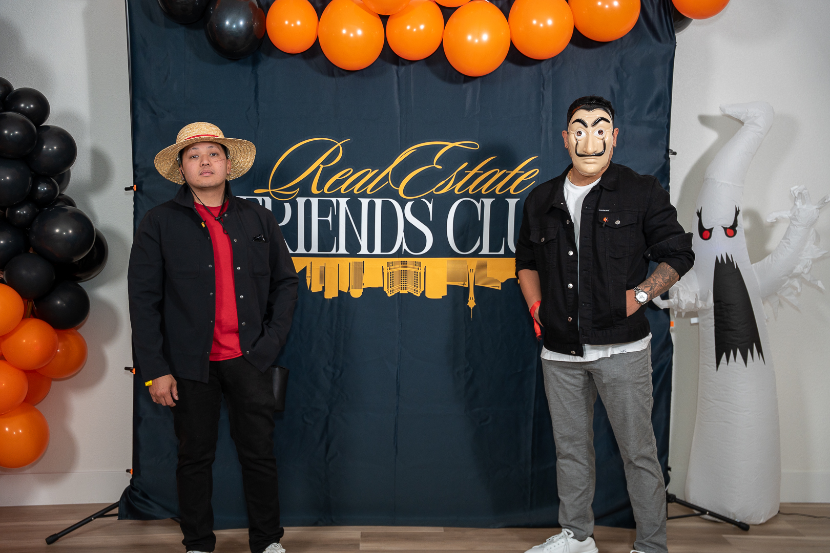 Two guests posing at the REFC backdrop in vampire and suit costumes