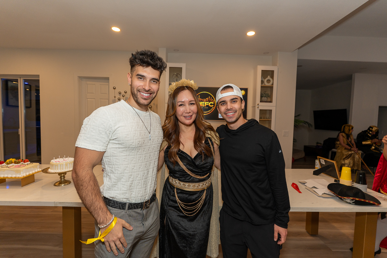 Three friends posing together in the kitchen after the anniversary celebration