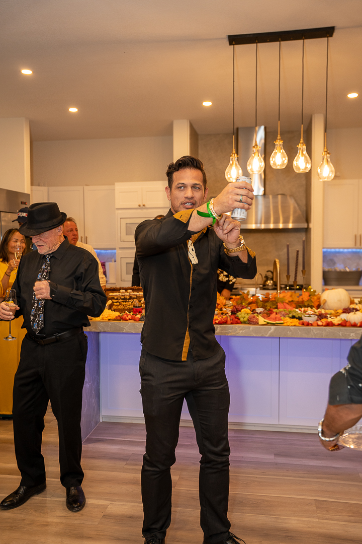 Guests raising a can and a glass of champagne beside the food spread