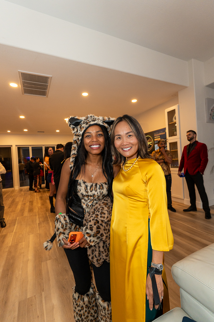 Two smiling guests in leopard and yellow costumes posing beside the sofa