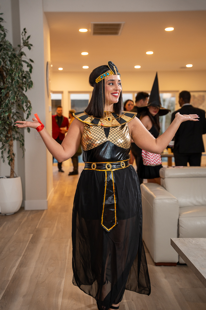 A guest in a black-and-gold Egyptian costume greeting friends with open arms