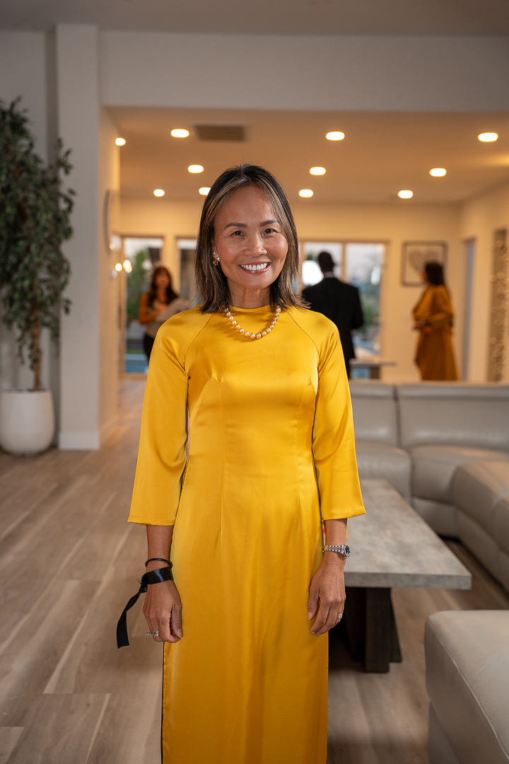 A guest in a yellow satin dress and pearl necklace smiling at the mixer