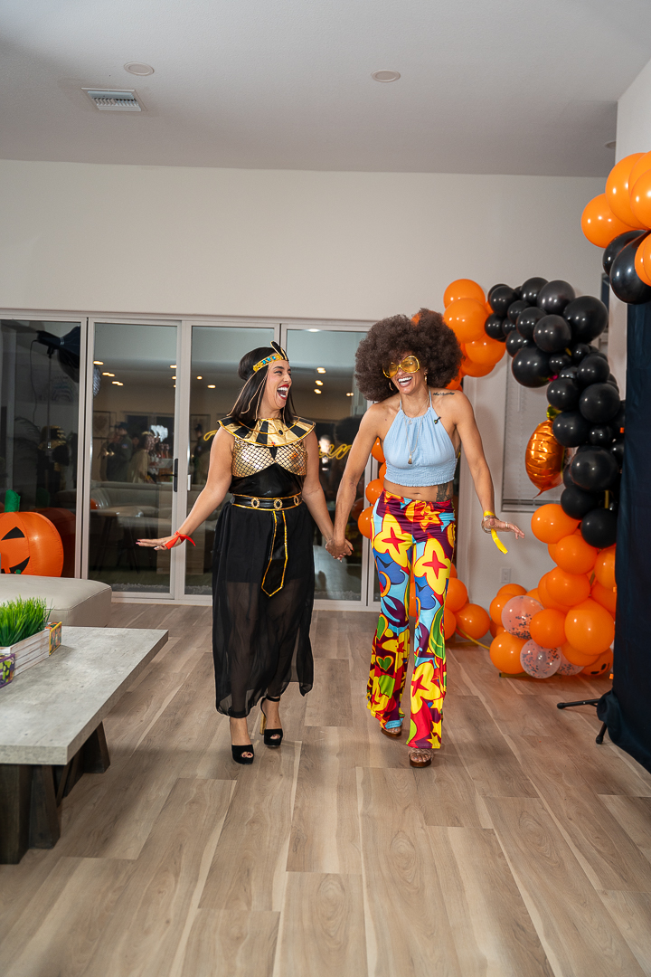 Friends in Egyptian-inspired and colorful disco costumes walking together at the mixer