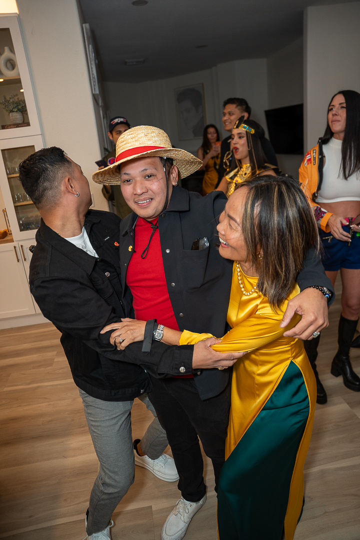 Three friends laughing and embracing during the REFC anniversary mixer