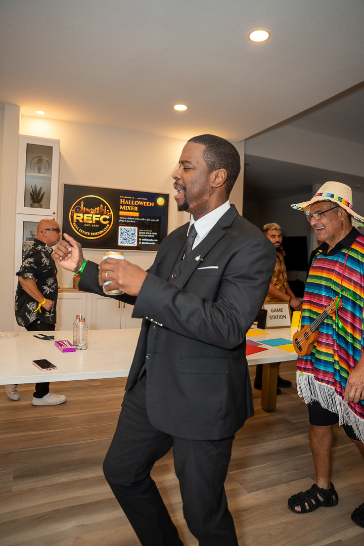 A guest in a suit dancing with a drink during REFC's first-anniversary celebration
