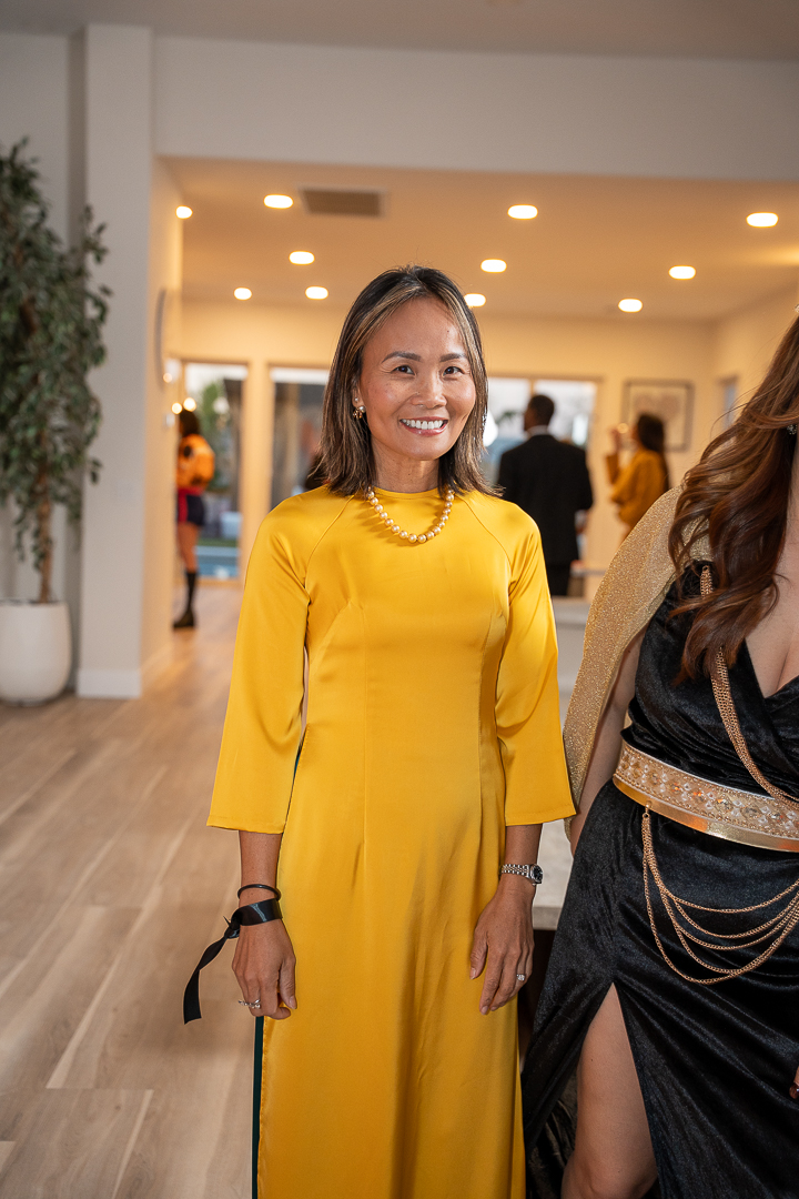 A guest in a yellow dress laughing with a friend in a black-and-gold gown