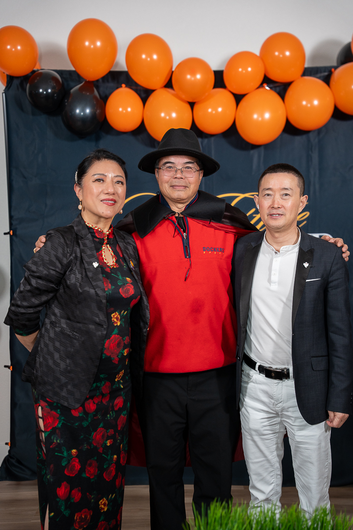 Three guests posing under the orange and black balloons