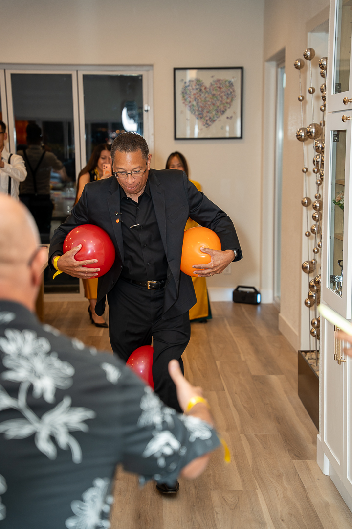A guest in a suit joining a party game with red and orange balloons