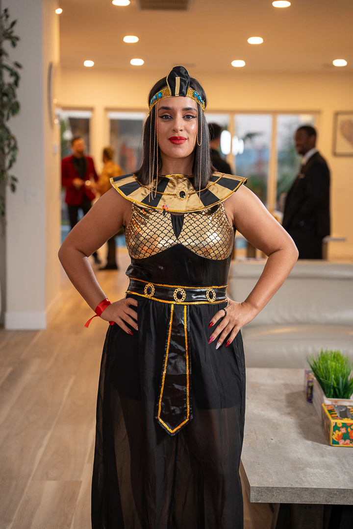 A guest posing in an Egyptian-inspired black-and-gold gown and headdress