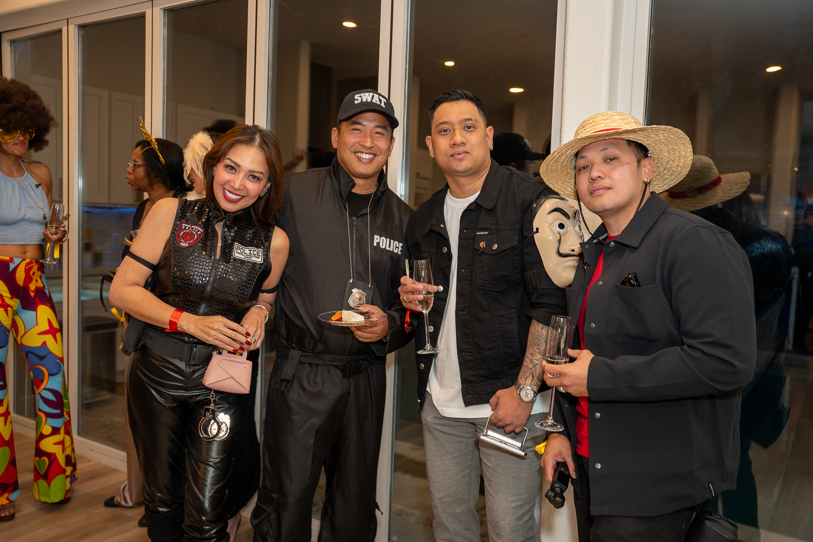 Four guests posing together in Halloween costumes near the kitchen