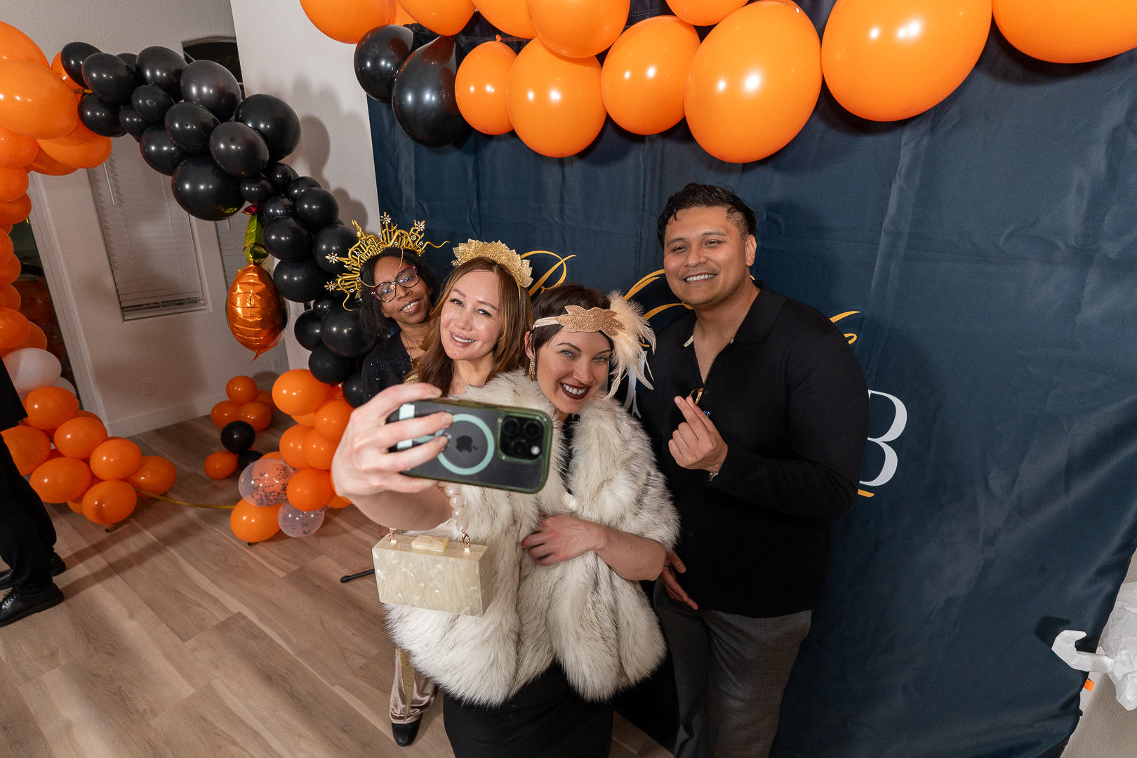 Friends posing with a small dog beneath the orange and black balloons