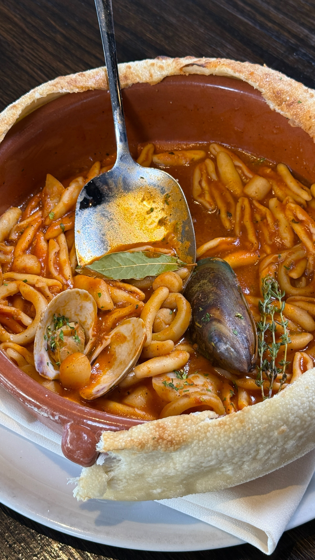 Seafood pasta served in a clay bowl with a bread crust rim