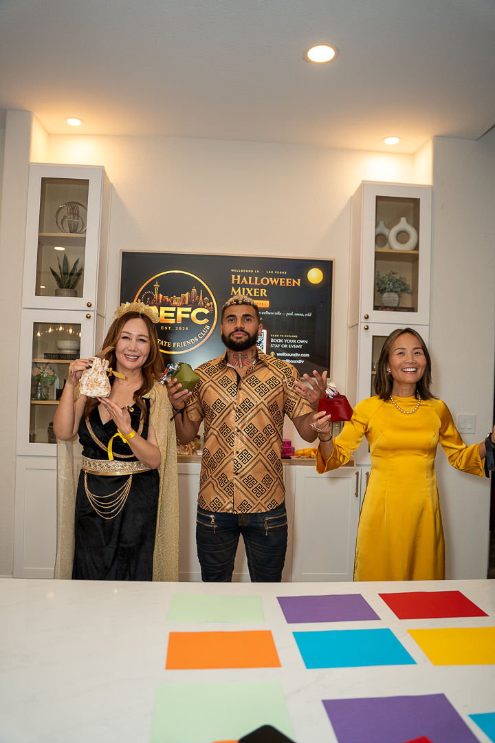 Three guests raising their drinks beside the REFC event sign