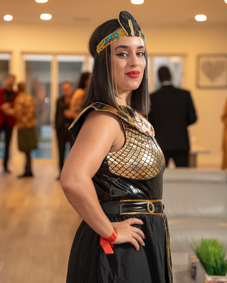 A guest in a black-and-gold Egyptian-inspired costume posing beside the sofa
