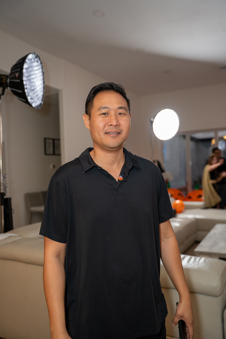 A guest in a black polo posing beside the event photography lights