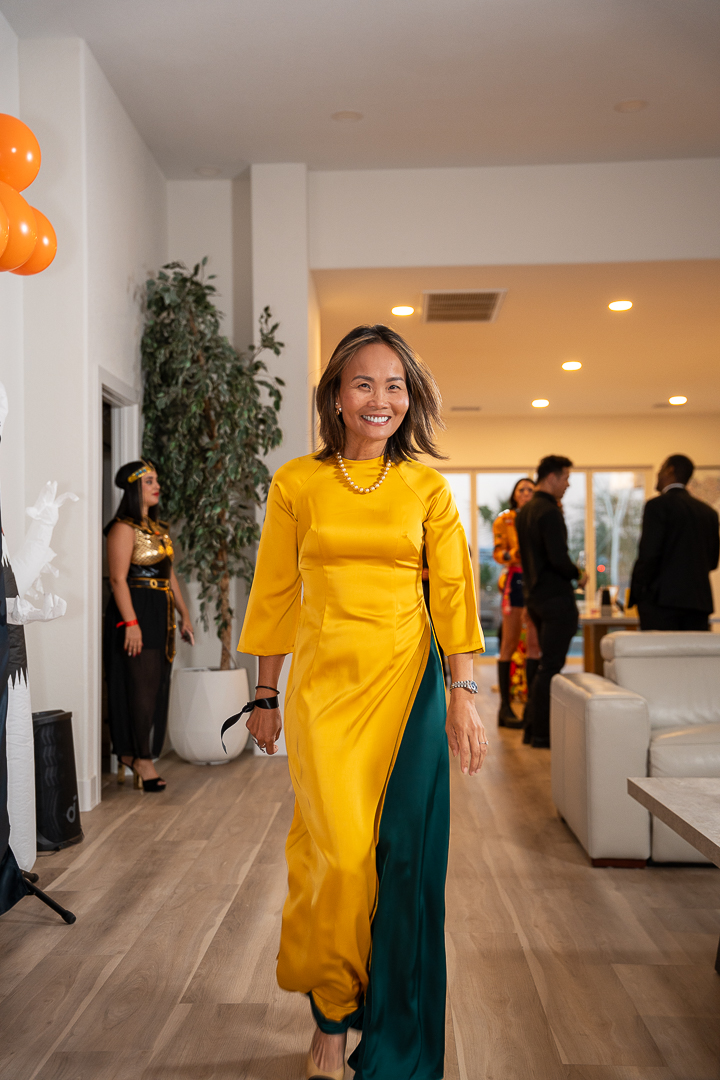 A smiling guest in a bright yellow outfit arriving at the Halloween mixer