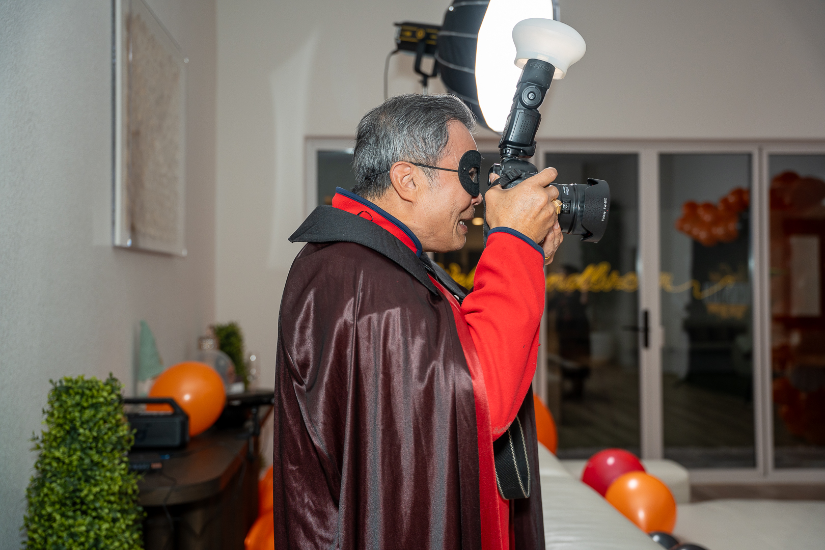 A costumed guest photographing the party with a camera and flash