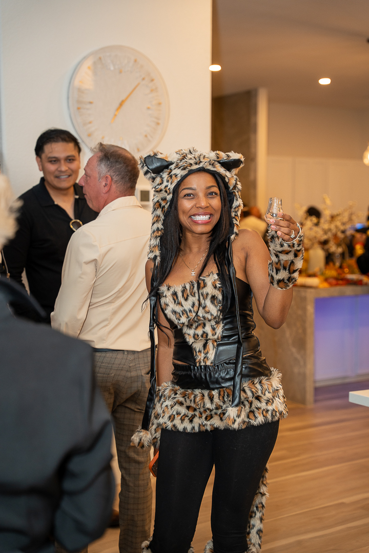 A guest in an animal-print costume smiling beside the kitchen