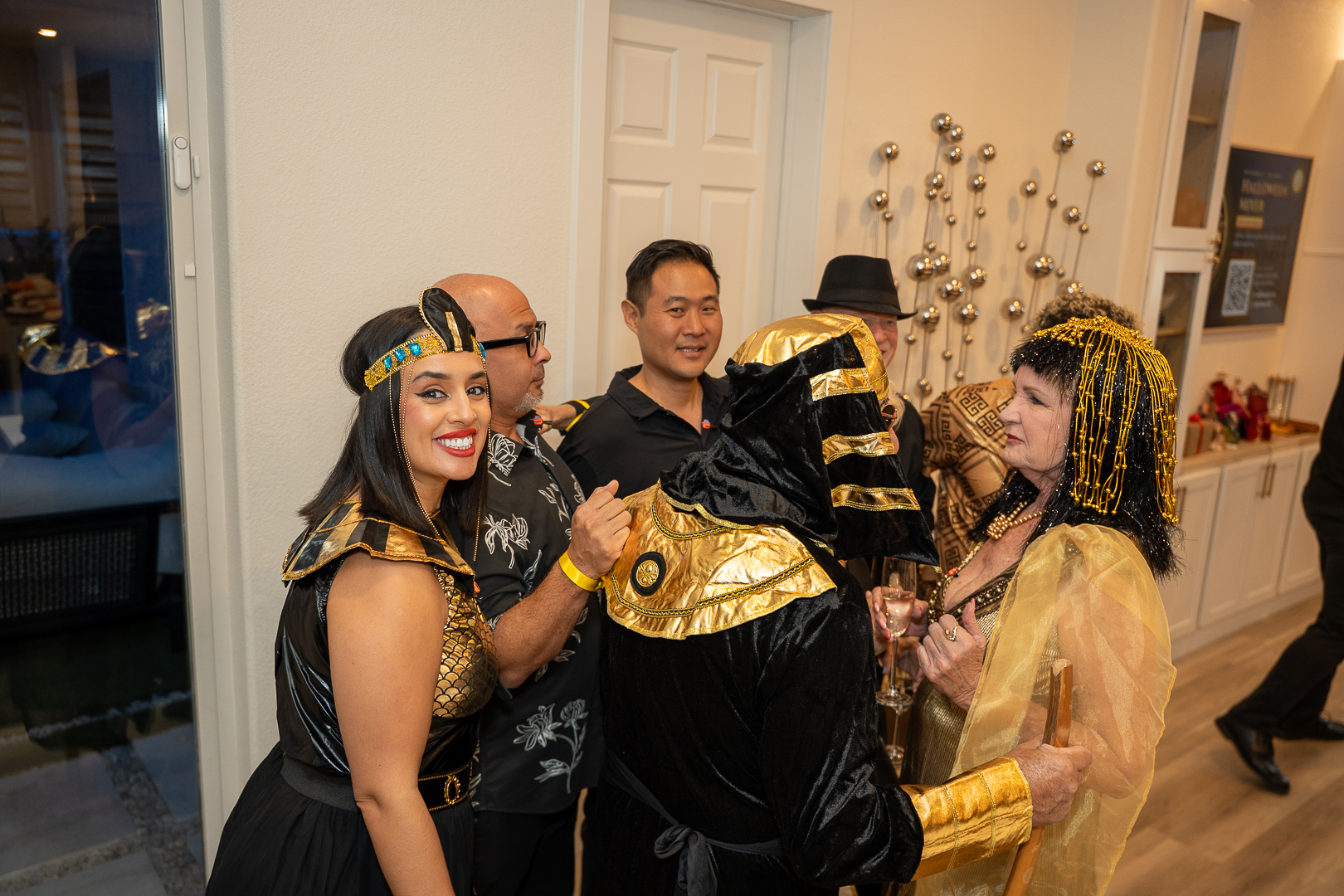 Friends in Egyptian-inspired costumes and gold outfits mingling at the Halloween mixer