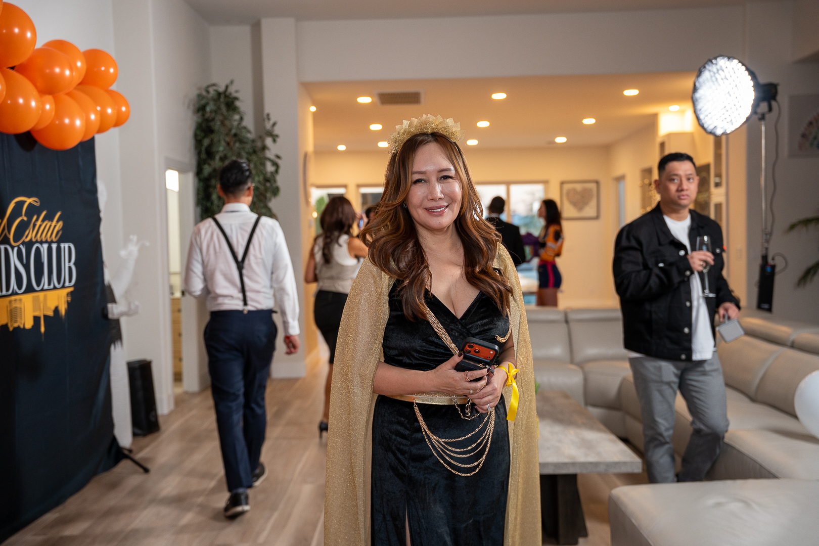 The queen-costumed hostess smiling with friends behind her at the mixer