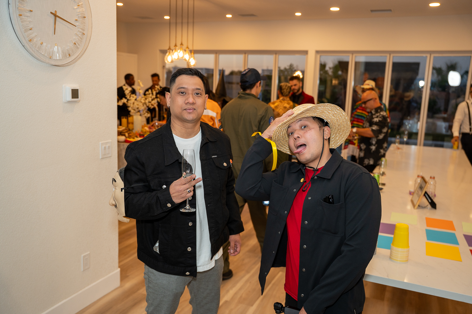 Two friends laughing as one tips his straw hat