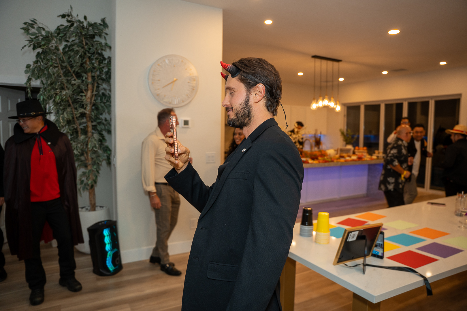 A guest in a suit telling a story beside the kitchen while a couple in costume arrives