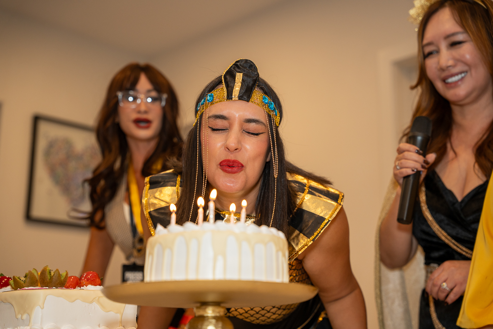 A guest in a pharaoh costume blowing out the candles on REFC's first-anniversary cake