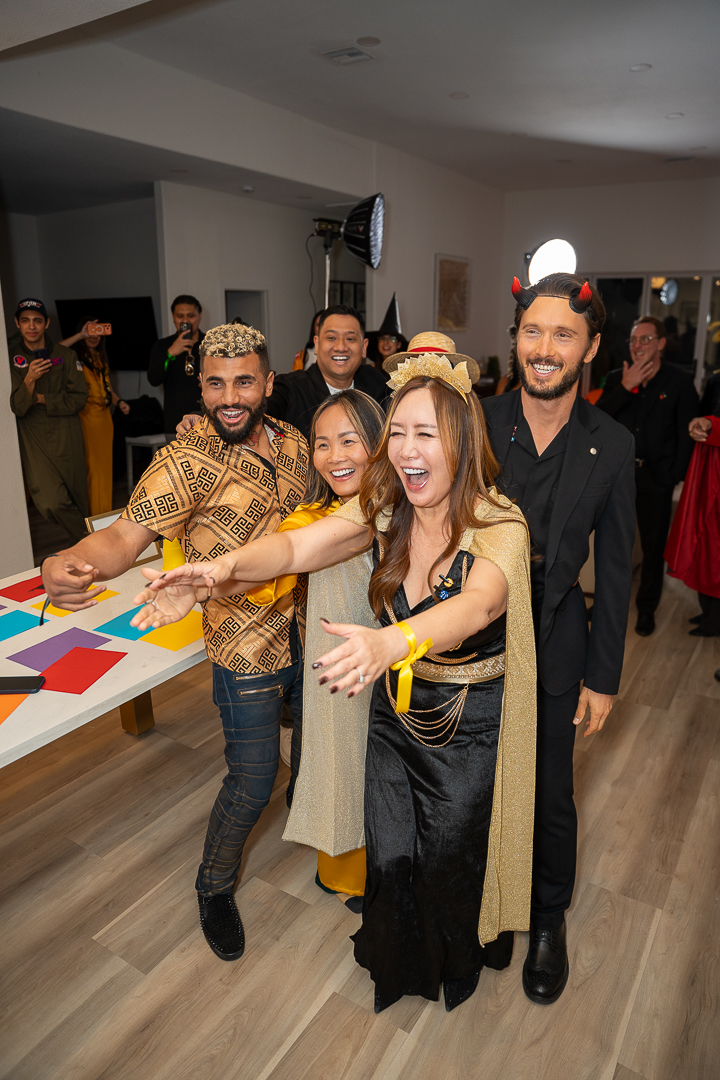 Smiling friends gathered beside the kitchen island in Halloween costumes