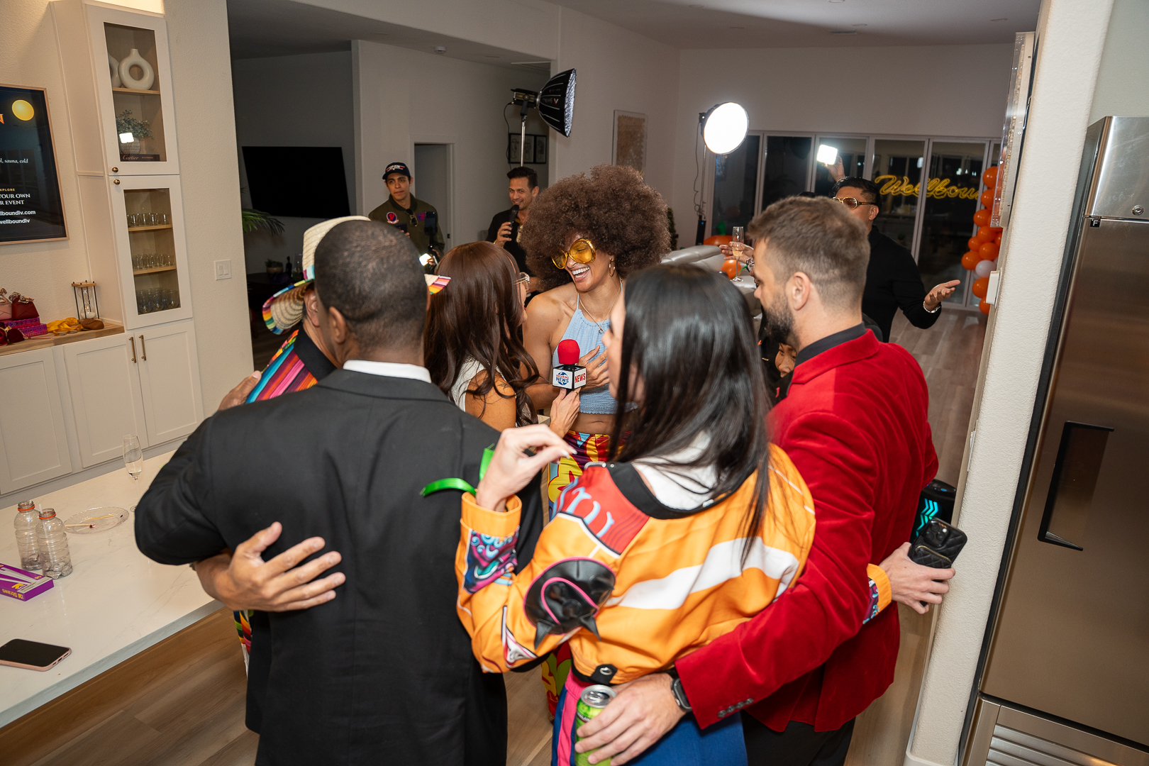 Costumed guests sharing a group embrace beside the kitchen island
