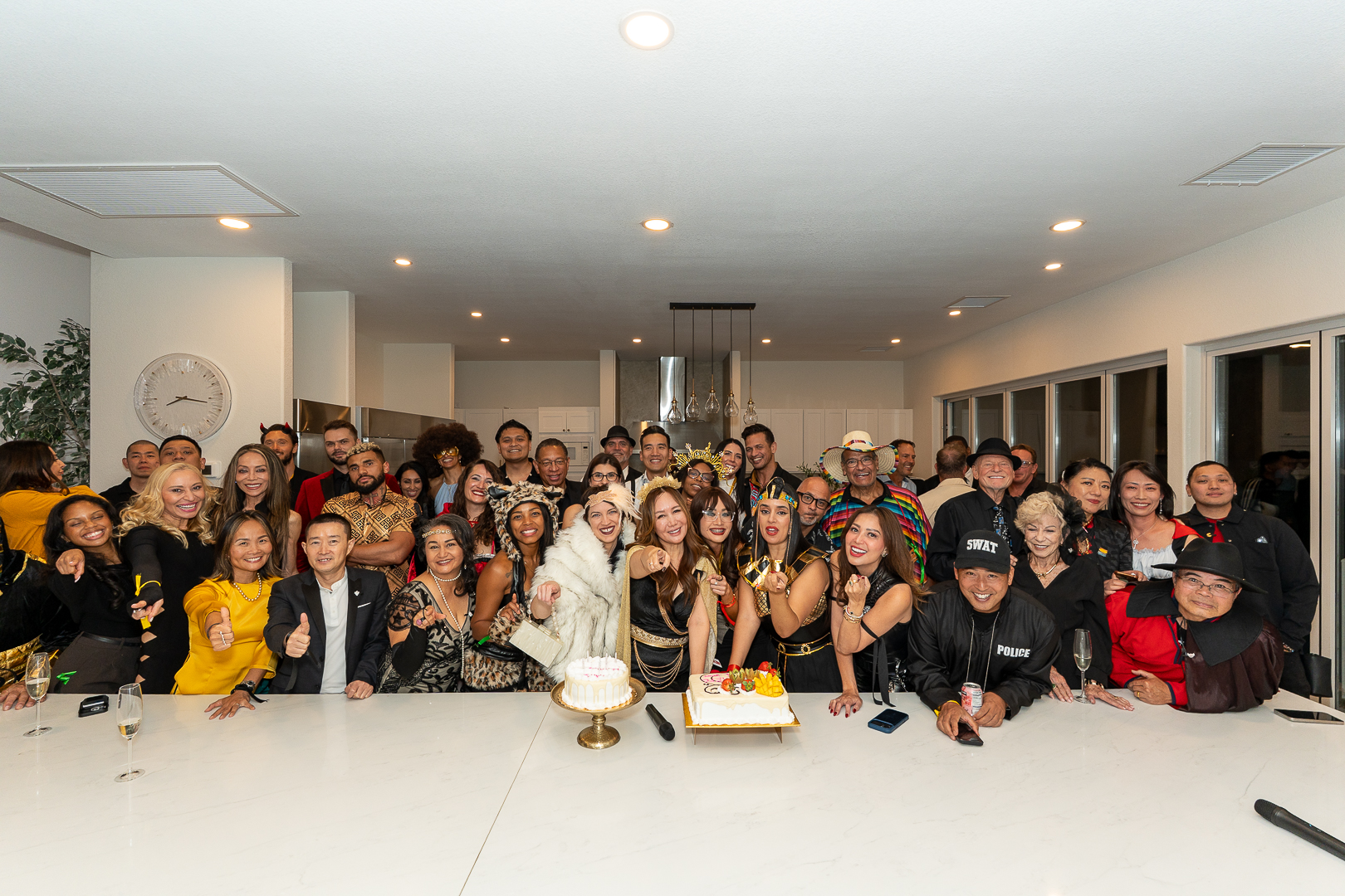 A wide group portrait of REFC guests gathered around the anniversary cake
