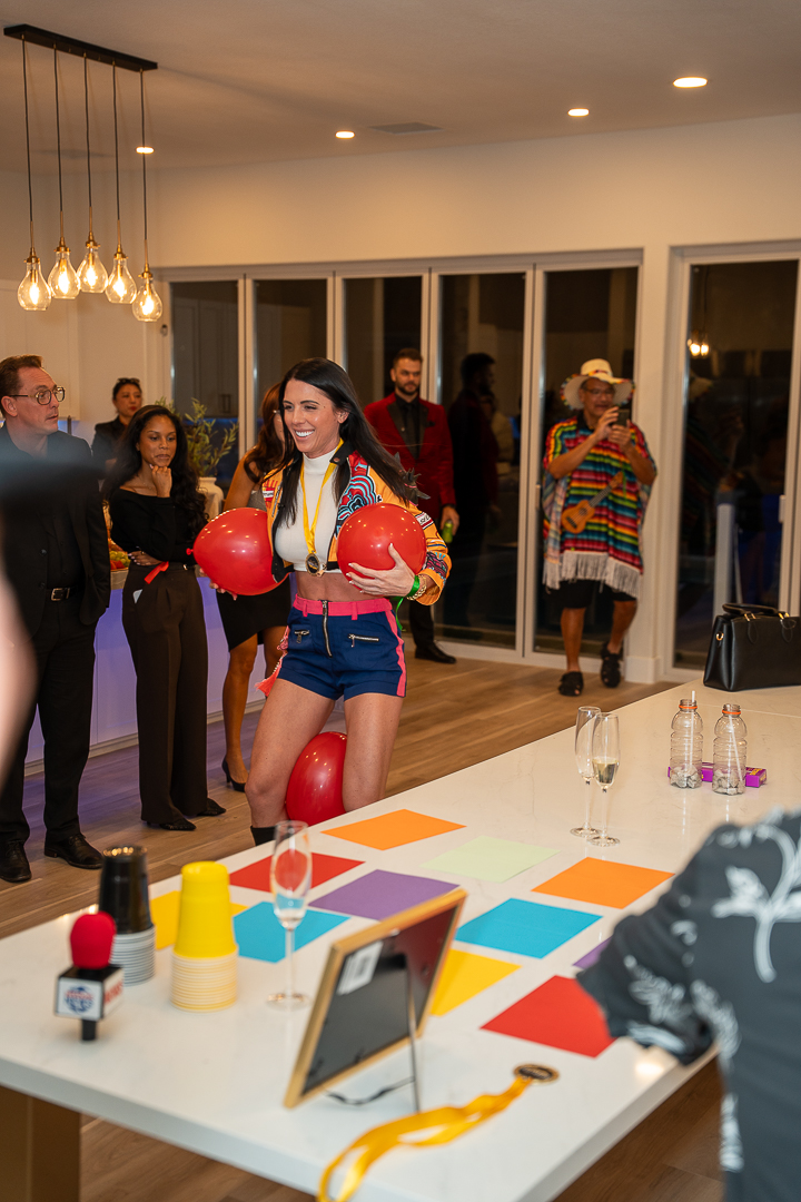 A costumed guest holding a red balloon during a party game beside the kitchen island