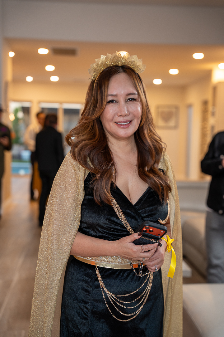 A smiling guest wearing a gold crown and black-and-gold costume