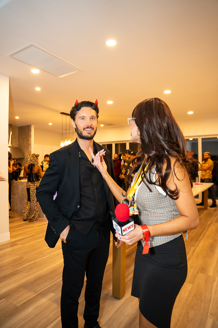 A guest in a reporter costume chatting with a man wearing red devil horns